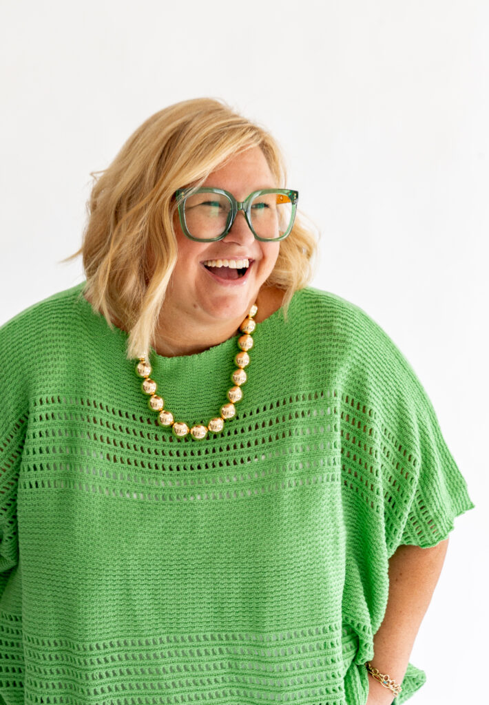 Kim laughing in her signature Kelly green sweater and green glasses